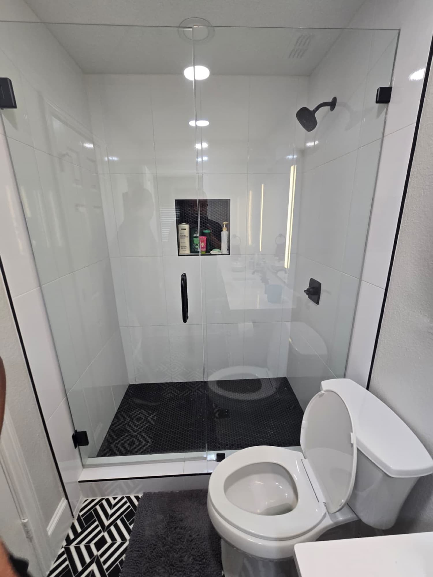 Modern black-and-white bathroom with glass shower and patterned tile