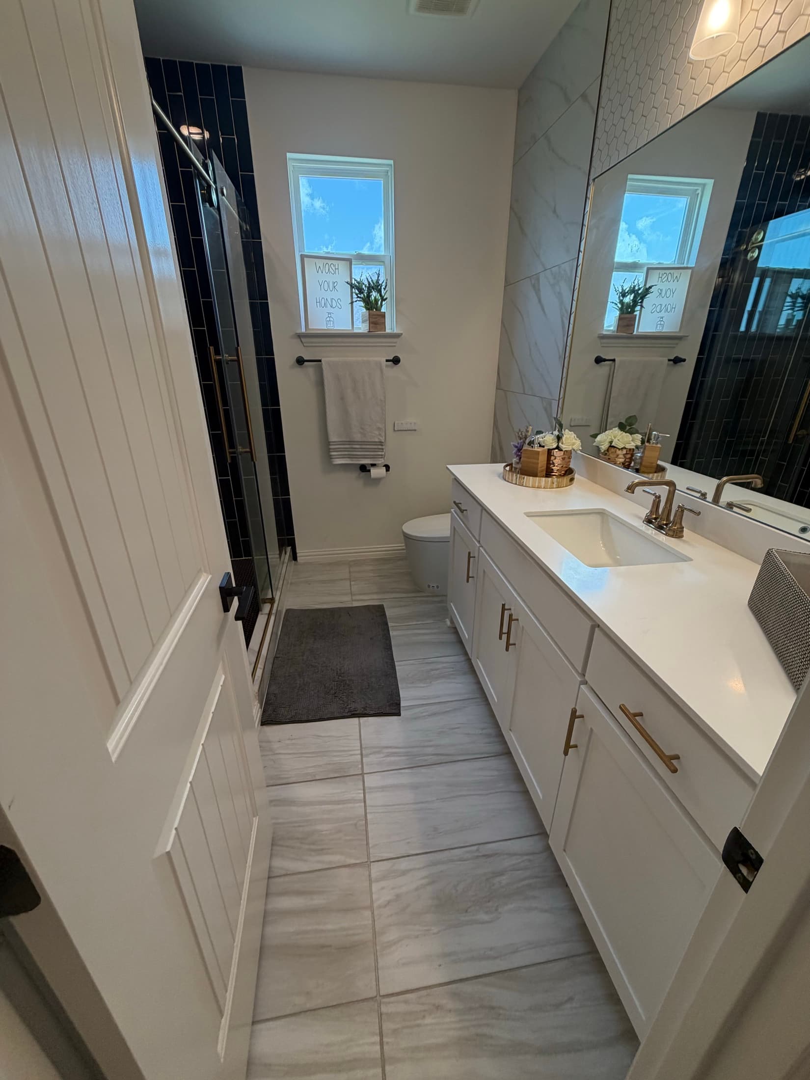 Master bathroom with navy tile shower and marble floor